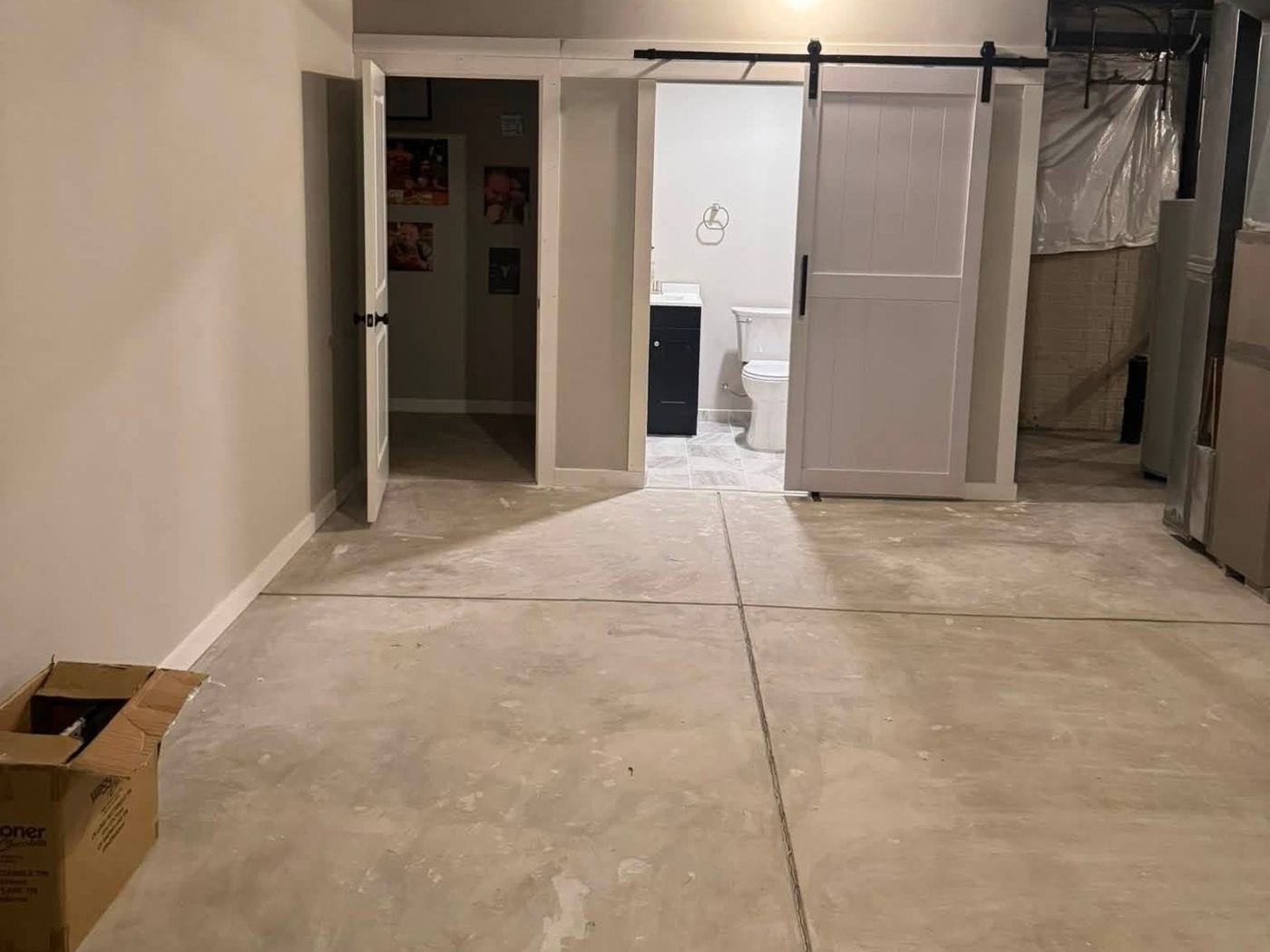 Finished basement with painted walls, trim and a bathroom behind a barn door