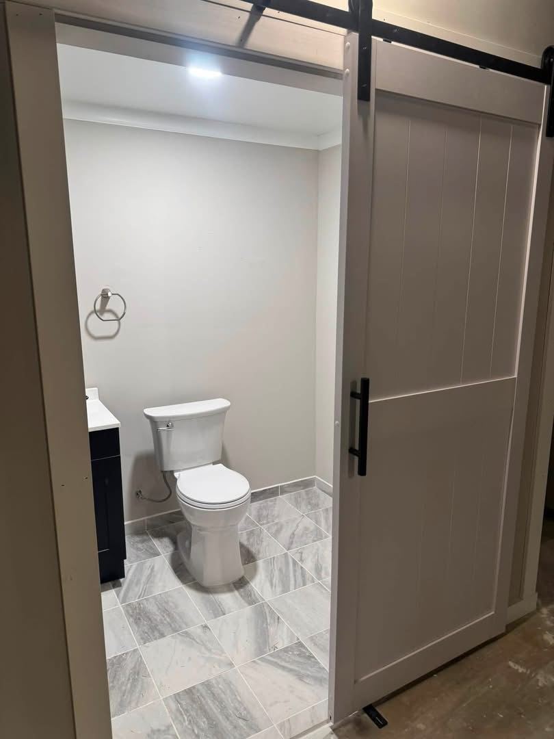Basement half bath. Tile floor, new fixtures and a barn door.