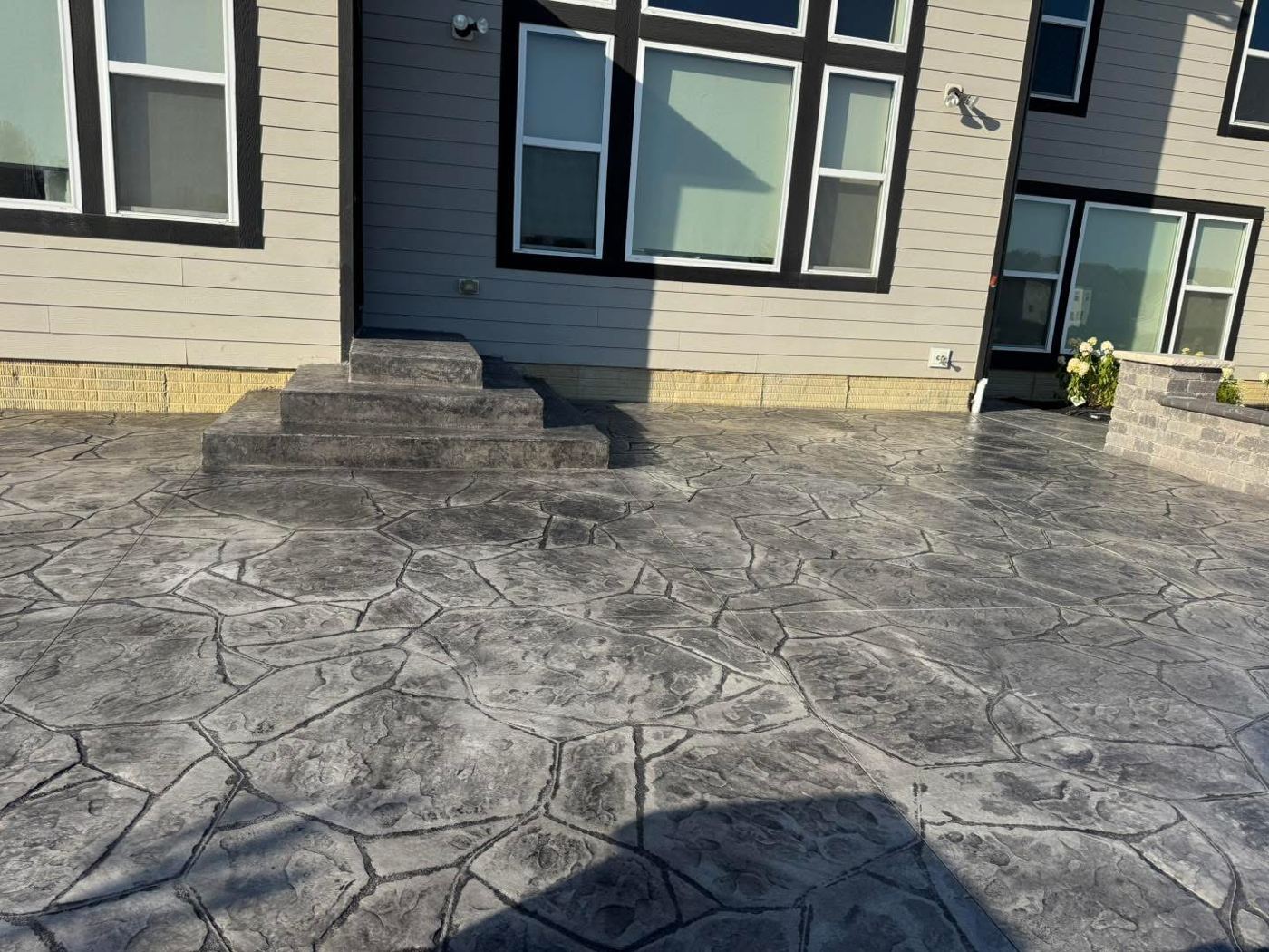 Flagstone-stamped patio. Charcoal stamped patio with matching steps.