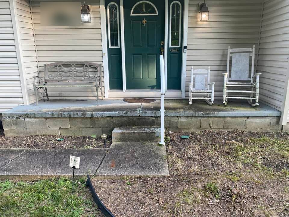 Old front porch with stained, worn concrete and a cracked step
