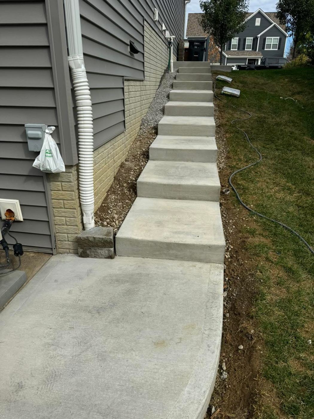 Steps up a slope. Poured concrete steps and landing along the house.
