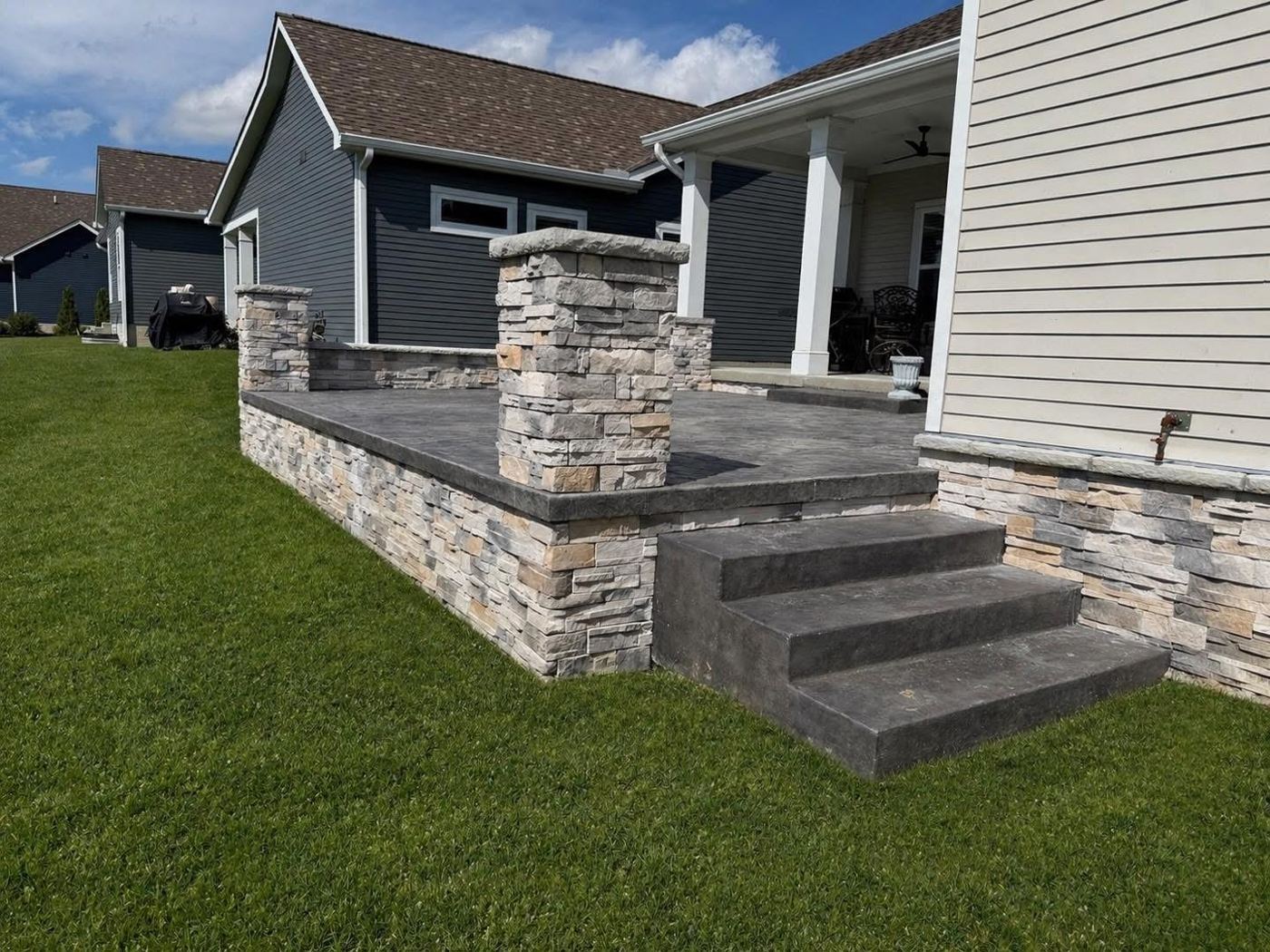 Stamped steps and stone pillars. Raised porch with stacked stone veneer.